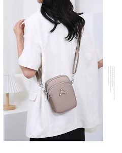 Detail view of khaki mini crossbody bag featuring triple-zipper layers and metal logo