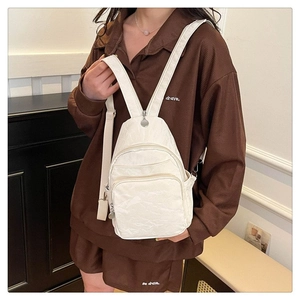Detail of white pleated texture chest bag with double front zippers and adjustable straps