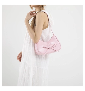 Dettaglio borsa hobo rosa con fiocco in pelle indossata da modella in abito pizzo