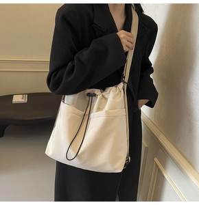 Detail of minimalist beige drawstring crossbody bag with large front pockets and fabric strap