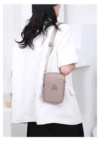 Detail of taupe multi-layer crossbody bag worn by model in a minimalist setting