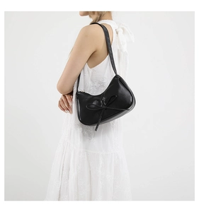 Dettaglio della borsa hobo in vernice nera con fiocco decorativo e finitura lucida