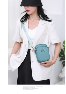 Close-up of teal nylon phone bag with double zippers and sport triangle metal logo plate