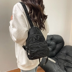 Detailed back view of a black pleated nylon mini chest bag with adjustable straps on a model
