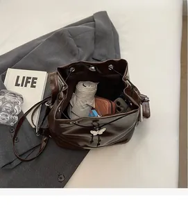 Vue intérieure montrant la grande capacité du sac seau en cuir marron avec objets