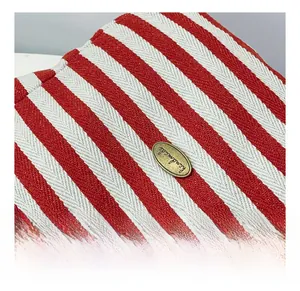 Detail of red striped canvas tote with bronze metal plate engraved with Handmade text