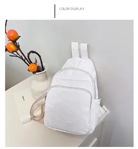 Detail view of cream white chest bag with unique wrinkled paper texture and double zippers