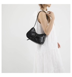 Borsa a spalla hobo nera minimalista con fiocco, indossata da una modella in bianco