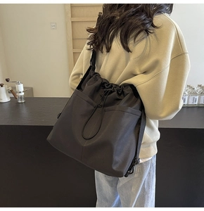 Detailed close-up of a black drawstring bucket bag with durable texture and adjustable strap