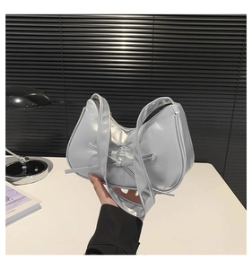 Dettaglio della borsa sottobraccio argento metallizzato con fiocco decorativo e pieghe