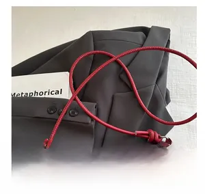 Détail du sac à épaule en cuir matelassé rouge avec bandoulière nouée sur veste