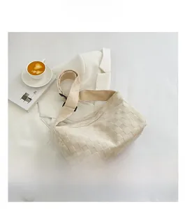 Detail shot of beige woven hobo bag with wide shoulder strap on a minimalist lifestyle background