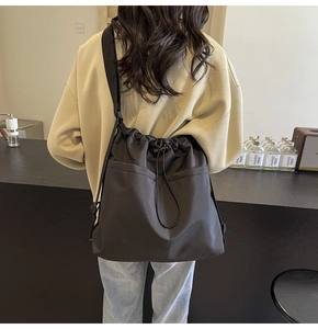 Close-up of minimalist black drawstring crossbody bucket bag with dual front pockets