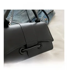 Close-up detail of the black leather crossbody bag with unique bar closure and metal rings
