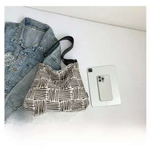 Flat lay of woven tote bag with adjustable strap next to a tablet and denim jacket