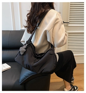 Detail van de grote zwarte nylon hobo tas met een geblokte hartvormige bedel als accessoire
