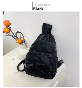 Detail of black crossbody bag featuring pleated texture and multiple zipper pockets