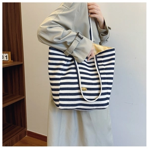 Detail of blue and white striped canvas tote bag with thick rope handles and gold tag