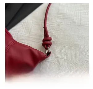 Détail d'un sac en cuir rouge avec anneau en métal argenté et bandoulière à nœud chic