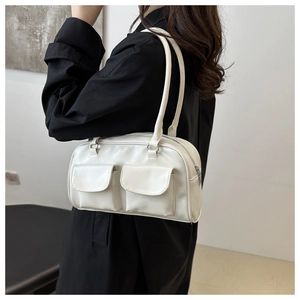 Détail d'un sac à main blanc rectangulaire avec deux poches frontales et boucles argent