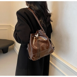 Détail du sac seau marron brillant avec boucle papillon argentée et fermeture à cordon