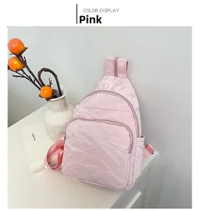 Pink textured fabric chest bag featuring multiple zipper compartments and durable strap
