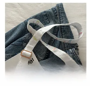 Détail de la bandoulière brodée blanche réglable avec boucle en métal doré