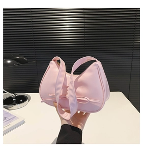 Borsa a mezzaluna rosa con fiocco decorativo mostrata in un ambiente casual