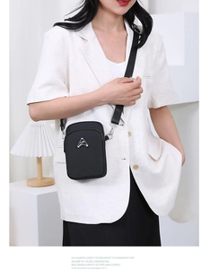 Detail of black nylon crossbody phone bag with double zippers and adjustable strap