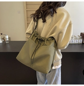 Detail of olive green canvas drawstring tote bag showing large capacity and side pockets