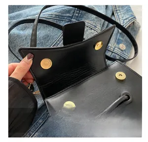 Detail of minimalist black PU leather handbag with dual gold magnetic snap closures