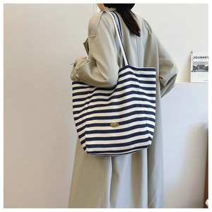 Detail of blue and white striped canvas tote bag worn with a stylish beige trench coat