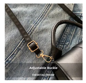 Detail of adjustable black leather shoulder strap with polished gold-tone metal buckle