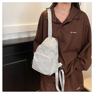 Detail of silver pleated fabric and front zipper pocket on the modern chest bag