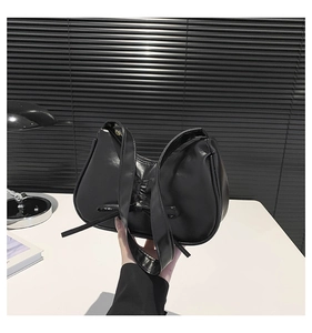 Dettaglio borsa in pelle nera lucida con design a fiocco pieghettato e tracolla larga
