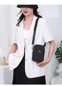 Detail view of black nylon crossbody bag featuring metallic SPORT logo and dual zipper layers