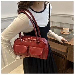 Détail d'un sac à main rouge en cuir verni brillant avec deux poches et longues anses
