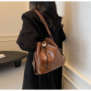Sac seau marron avec boucle papillon argentée et cordon de serrage sur le modèle