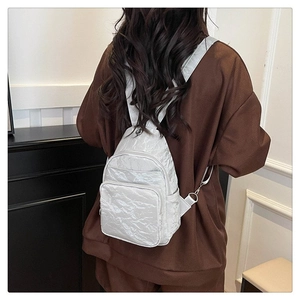 Detail of white mini backpack with stylish crinkled texture and multi-zippered pockets