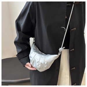 Détail du sac croissant argenté avec plis matelassés et bandoulière à nœuds