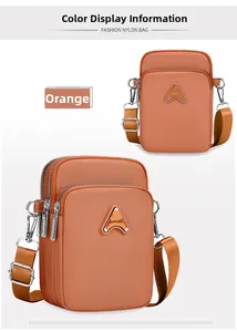 Detail view of orange nylon crossbody bag with multi-layer zippers and metal sport logo