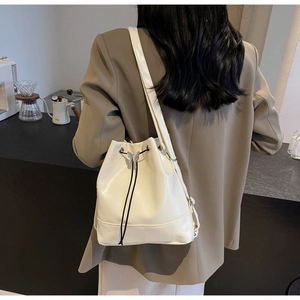 Détail du sac seau blanc crème avec cordon de serrage et breloque papillon argentée