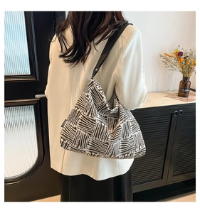 Detail of the large woven tote bag featuring a black and white geometric pattern and side tag