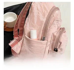 Detail view of pink pleated mini backpack showing functional side pocket with lipstick