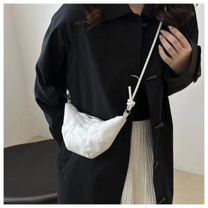 Détail du sac croissant blanc avec texture plissée et élégant nœud sur la bandoulière