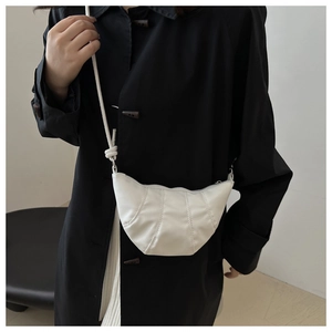 Détail du sac croissant blanc en cuir plissé avec bandoulière sur un manteau noir