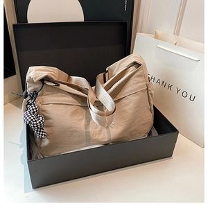 Detail van beige nylon crossbodytas met geruite knoop in een zwarte luxe geschenkdoos