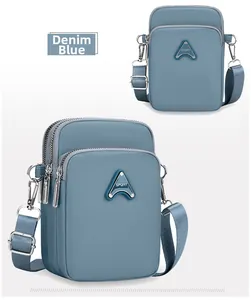Detail of denim blue crossbody bag with multiple zipper layers and SPORT badge