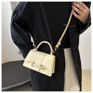 Chic cream-colored crossbody bag featuring gold hardware and unique perforated strap detail