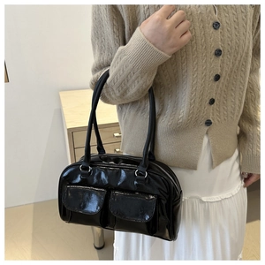 Détail du sac à main en cuir verni noir avec deux poches avant et finition brillante